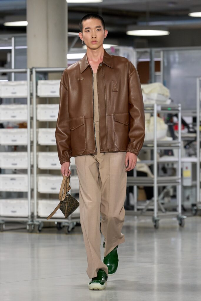 A relaxed brown leather jacket with long sleeves paired with straight-leg beige pants.