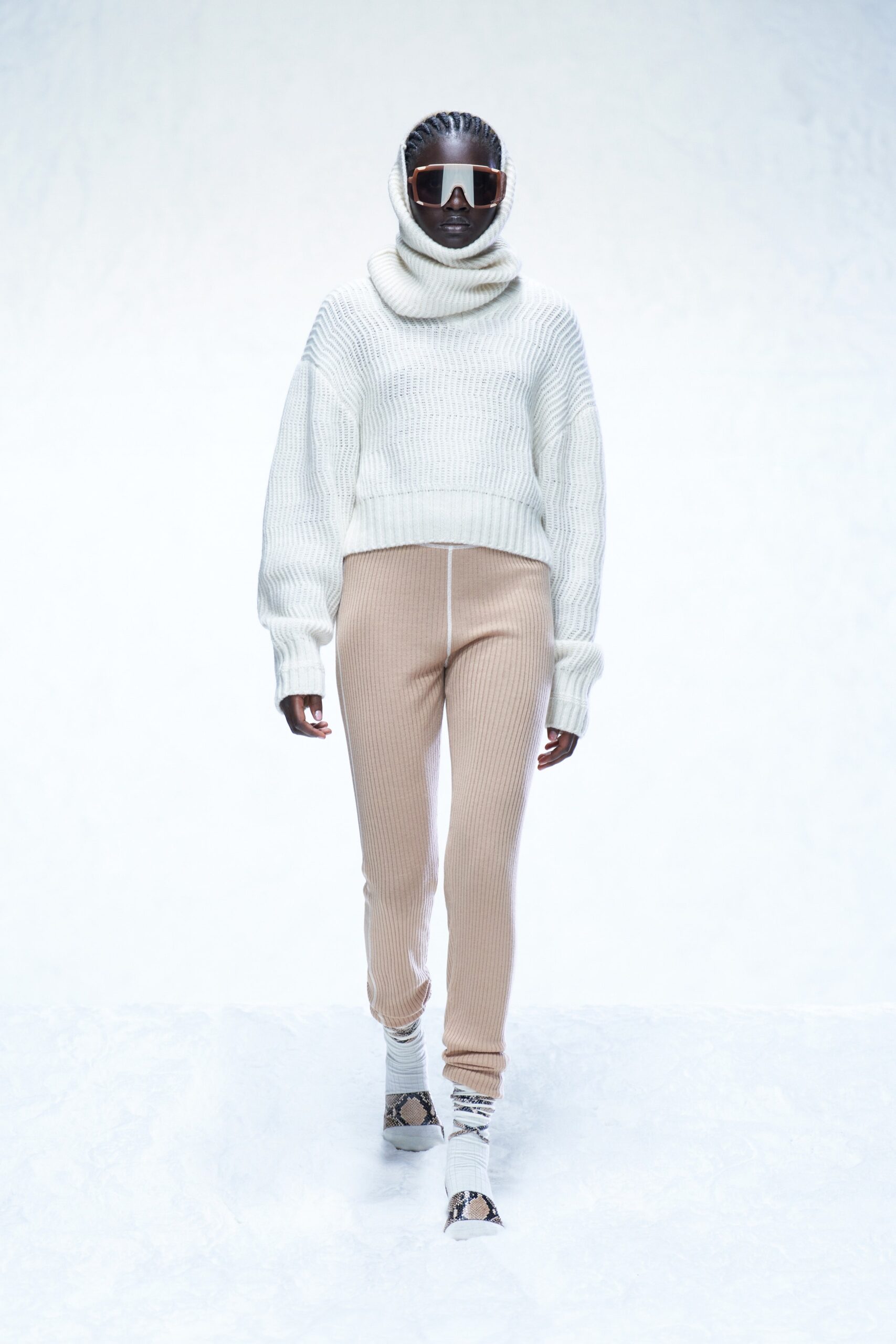 A relaxed white long-sleeve turtleneck sweater paired with ribbed beige pants.