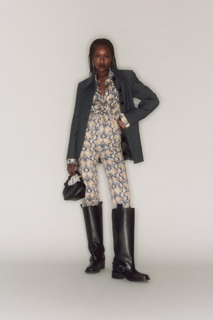 A fitted black jacket with long sleeves paired with printed pants in blue tones.