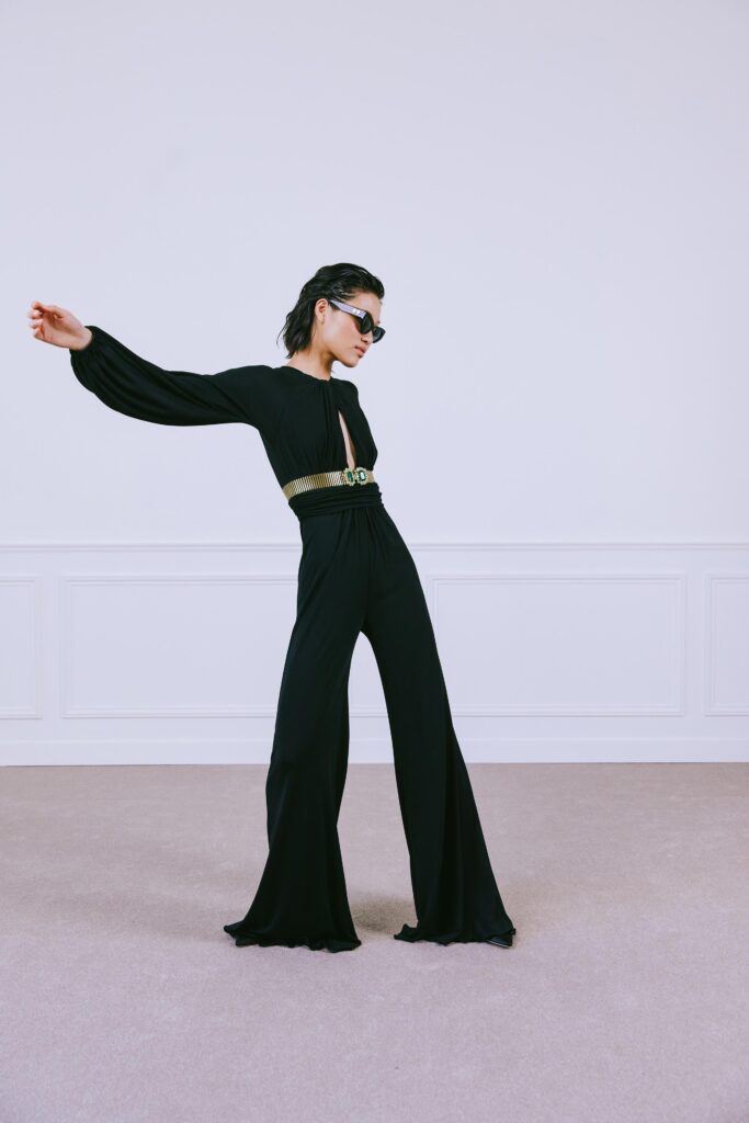 A fitted black jumpsuit with long sleeves and a V-neckline, featuring a flared silhouette.