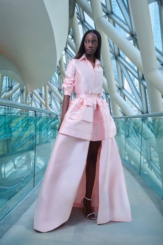 A fitted pink silk dress with long sleeves, a collared neckline, and a tiered design.