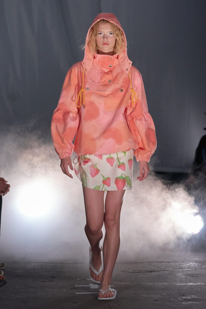 A relaxed orange cotton jacket with long sleeves and a collared design paired with a high-waisted printed skirt.