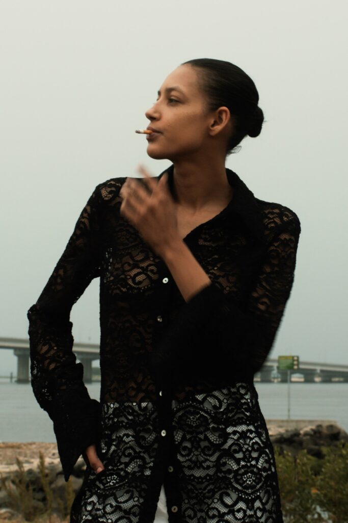 A fitted black lace dress with long sleeves and a collared design, featuring a layered look.