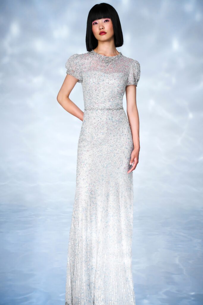 A fitted silver silk gown with short sleeves and a high neckline, adorned with sequins.