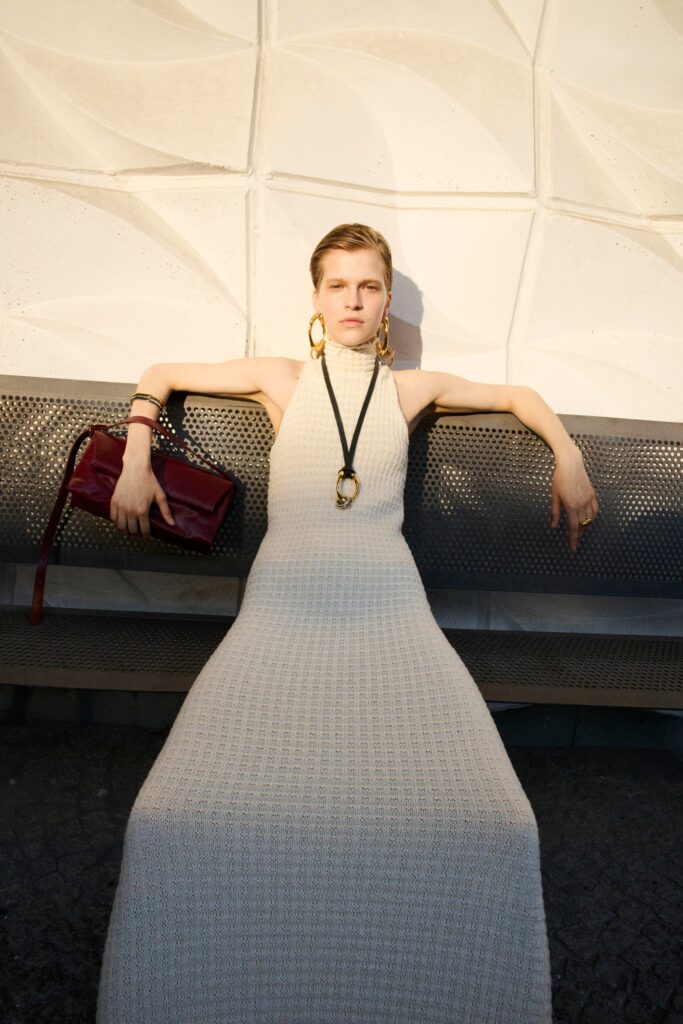 A fitted beige cotton dress with a sleeveless design and high-neck construction.