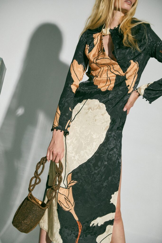 A fitted long-sleeve dress in black and beige with a V-neckline and asymmetric design.