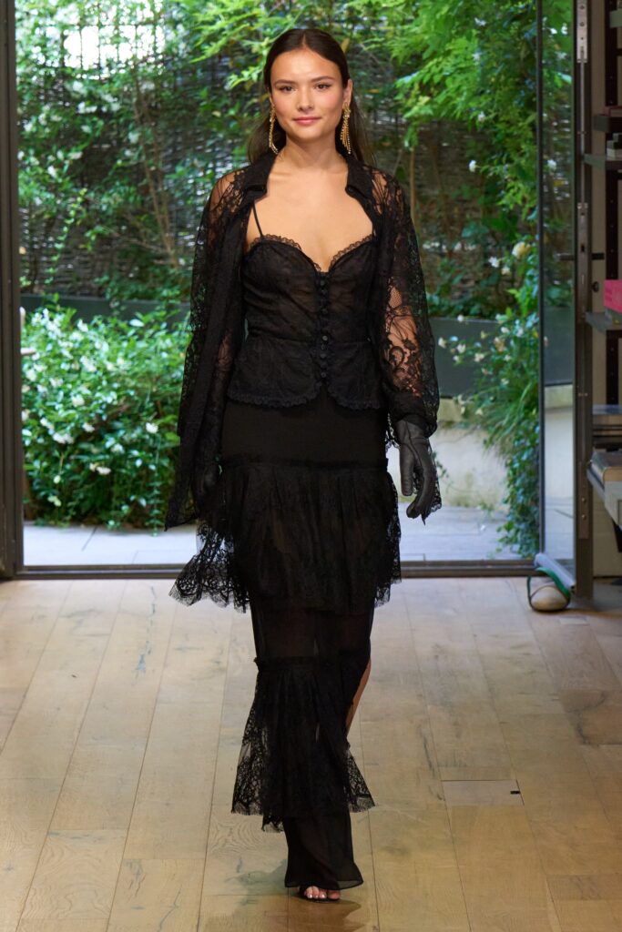 A fitted black lace sleeveless dress with a V-neckline and tiered design.