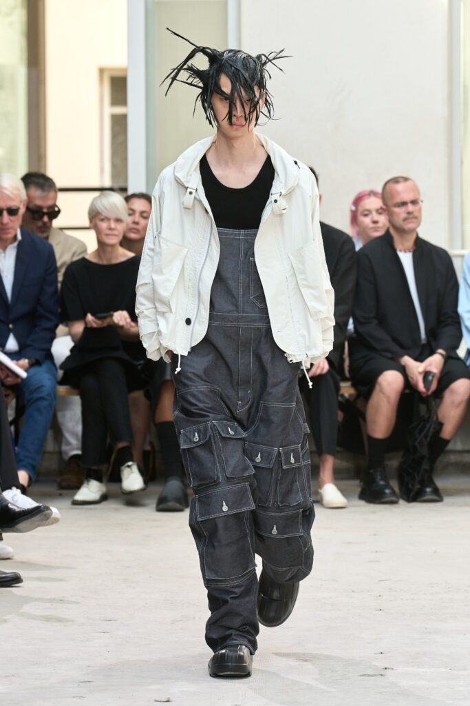 A relaxed fit white jacket paired with gray denim overalls featuring a zippered detail.
