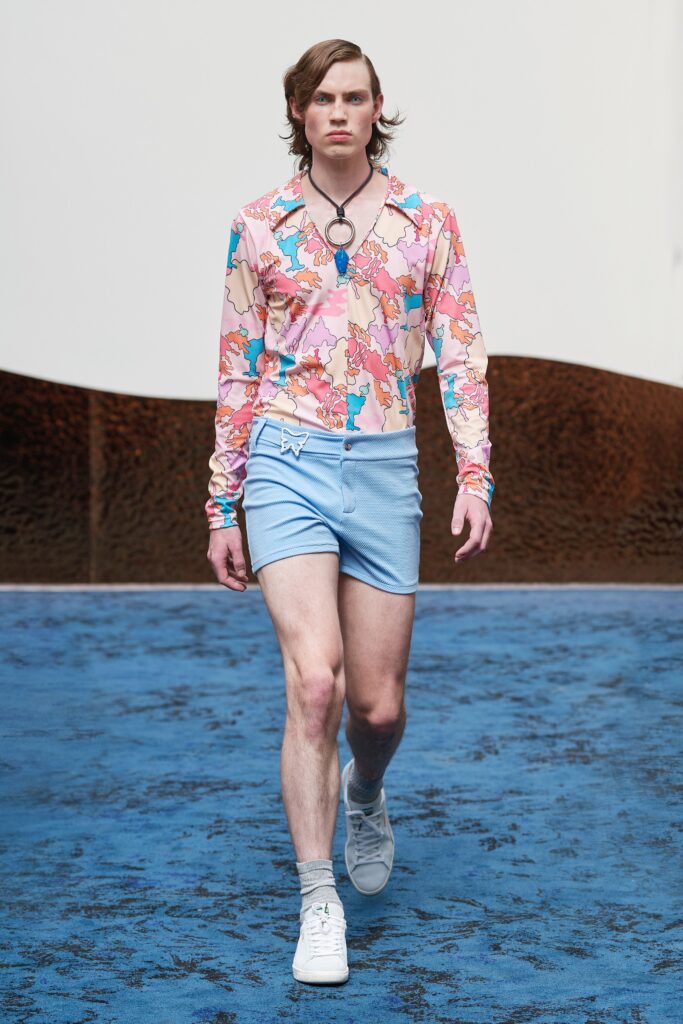 A fitted floral print long-sleeve shirt paired with fitted blue shorts.