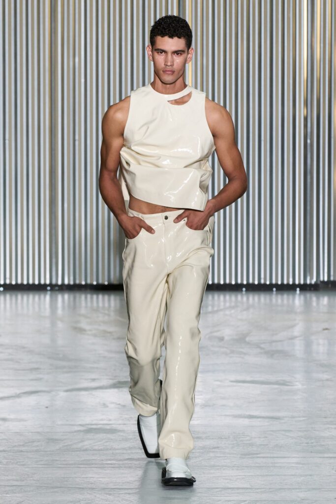 A fitted white leather sleeveless top with an asymmetric detail paired with matching pants.