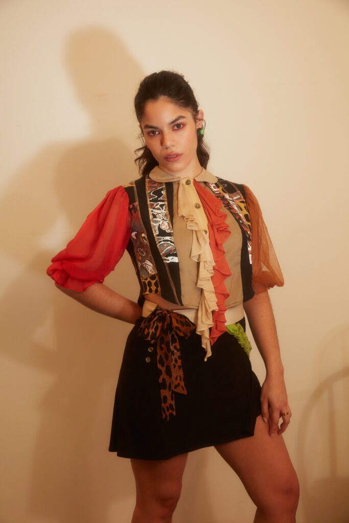 A fitted black and beige dress with short sleeves, a collared neckline, and ruffled asymmetric details.