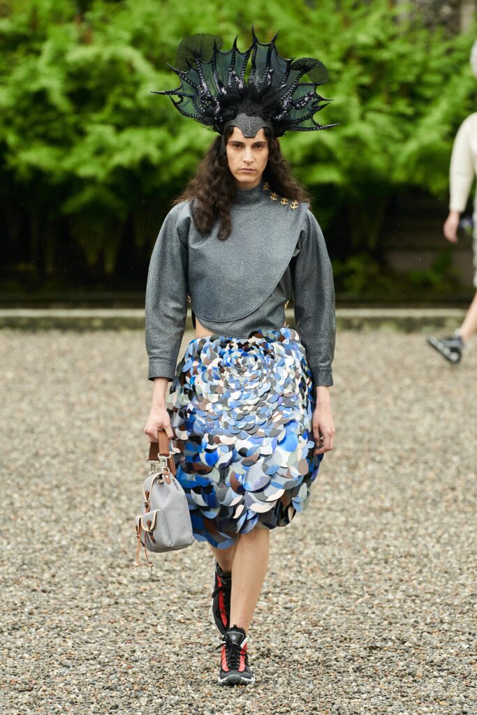 A fitted gray long-sleeve top with a high-neck and an asymmetric layered skirt in blue tones.