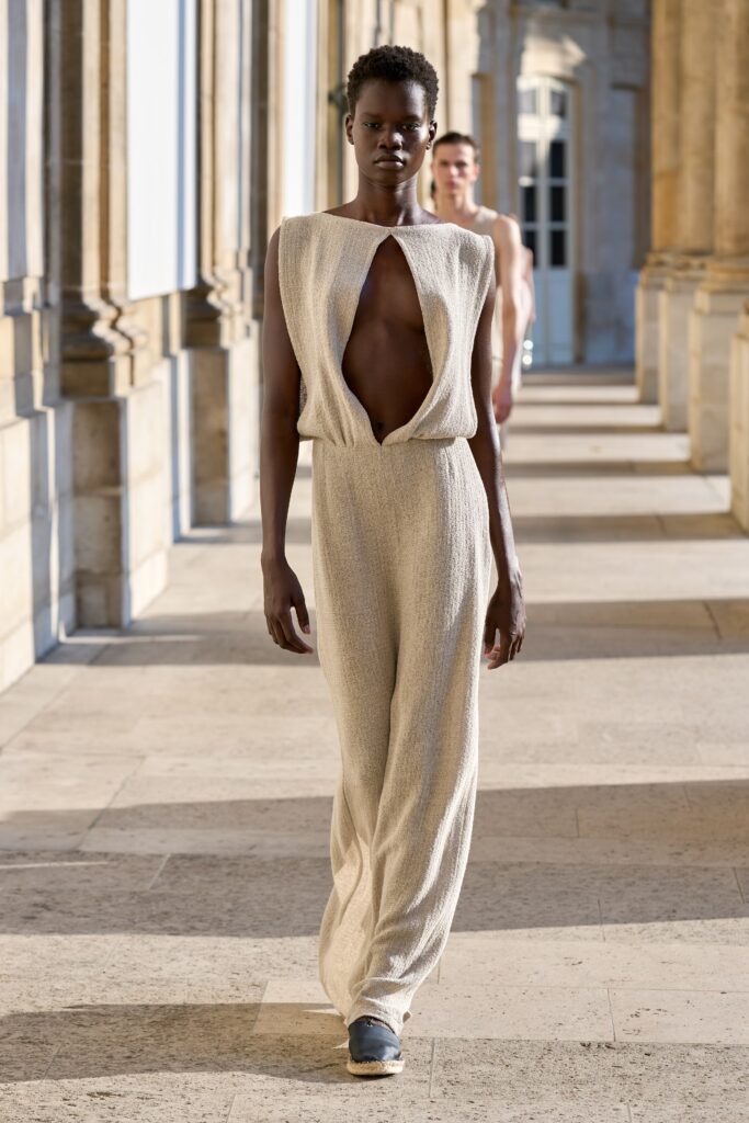 A relaxed beige silk sleeveless jumpsuit with an asymmetric design and V-neckline.