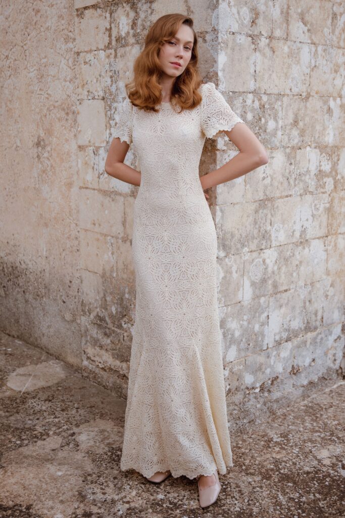 A fitted beige lace dress with short sleeves and a high neckline, featuring a maxi silhouette.