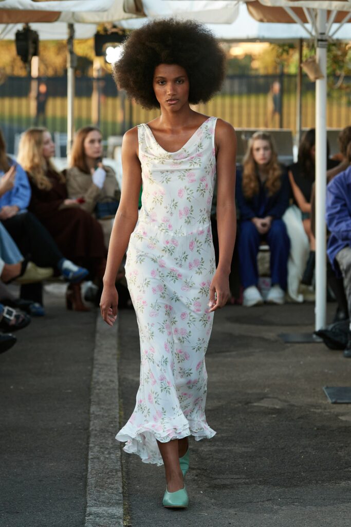 A fitted white silk sleeveless dress with a V-neckline and flared silhouette.