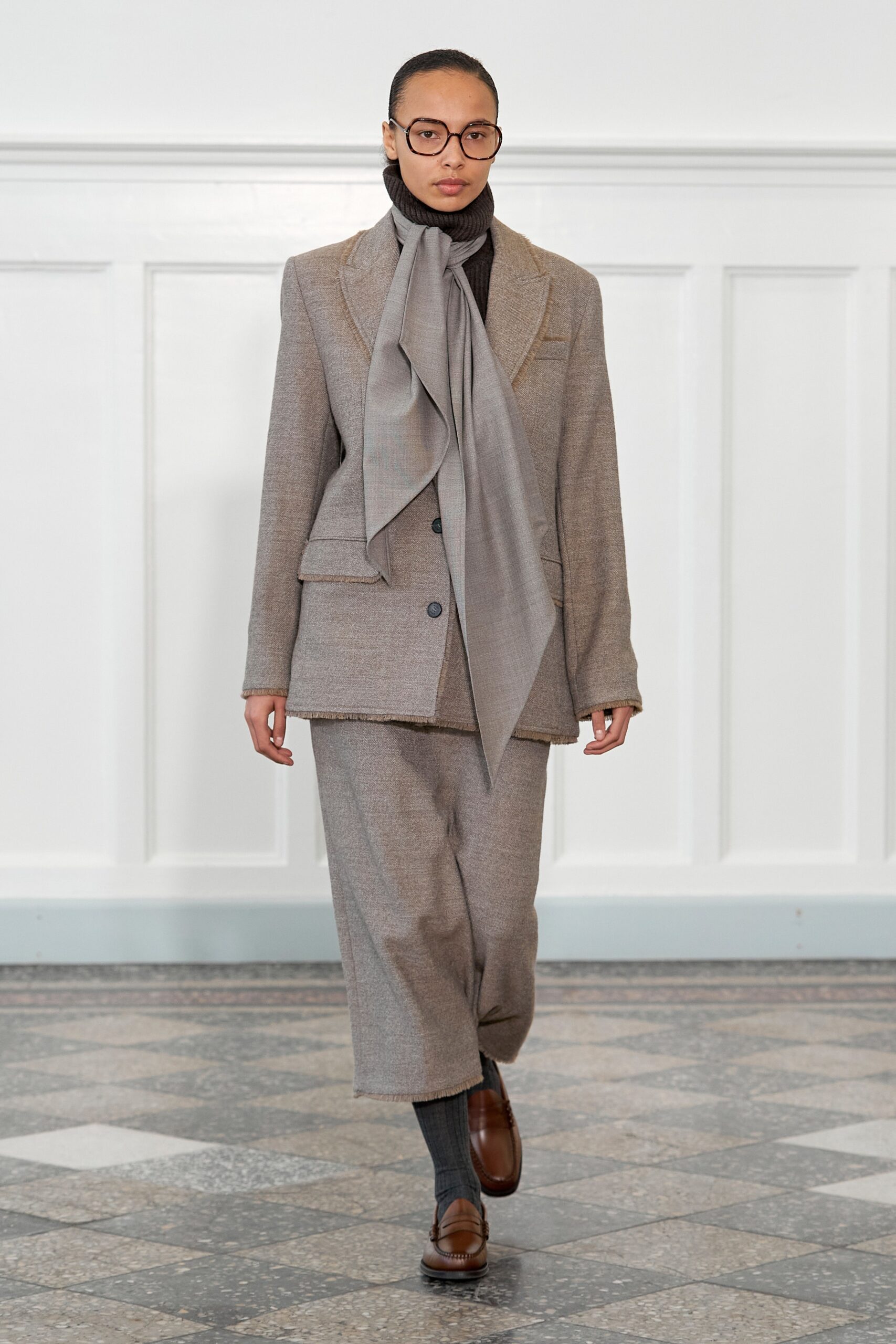A relaxed gray wool blazer with long sleeves and wide-leg pants, featuring a collared design.