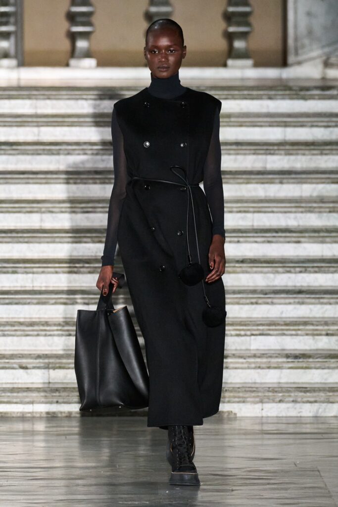 A fitted black wool dress with long sleeves, a collared neckline, and buttoned details.