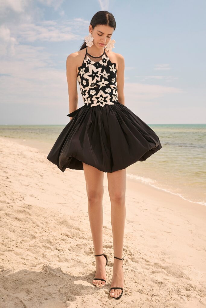 A fitted black and white sleeveless halter dress with a flared silhouette.