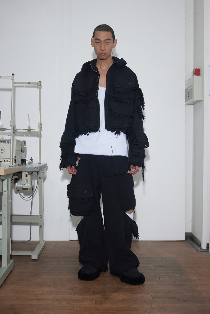 A relaxed black jacket with fringed details paired with matching pants, creating a layered look.