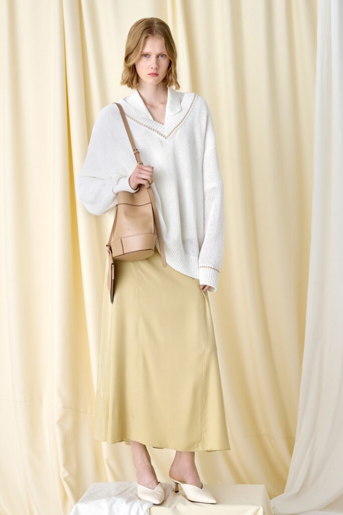 An oversized white long-sleeve top with a V-neck paired with a straight-leg yellow skirt.
