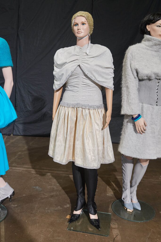 A fitted gray silk dress with a high neckline and pleated, tiered design.