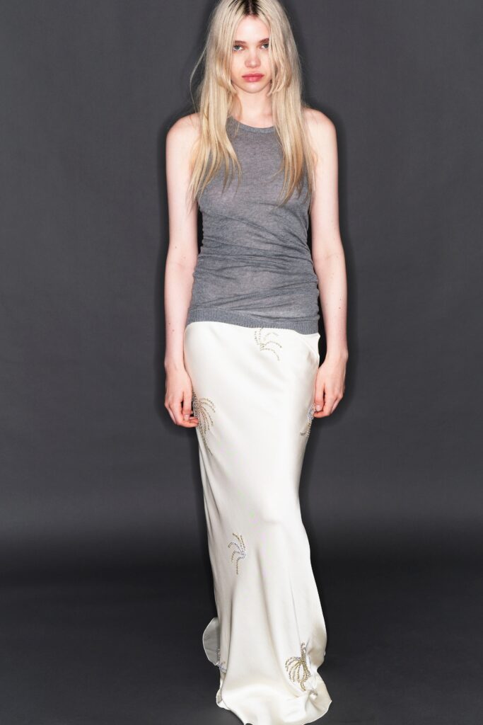 A fitted gray sleeveless top paired with a flowing white skirt featuring elegant design details.