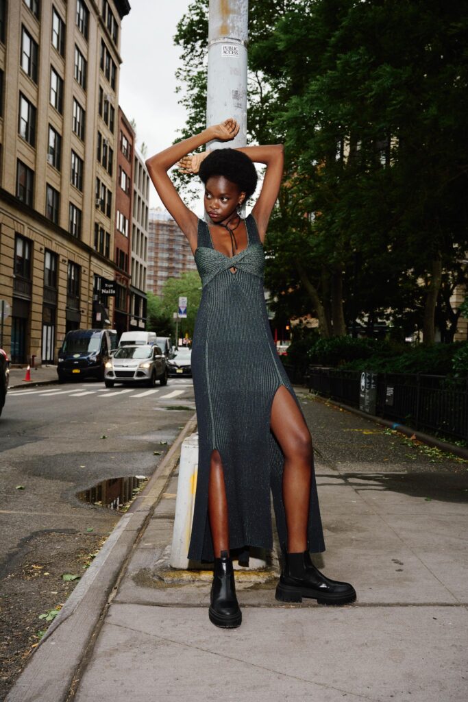 A fitted black cotton sleeveless dress with a V-neckline and side slit.