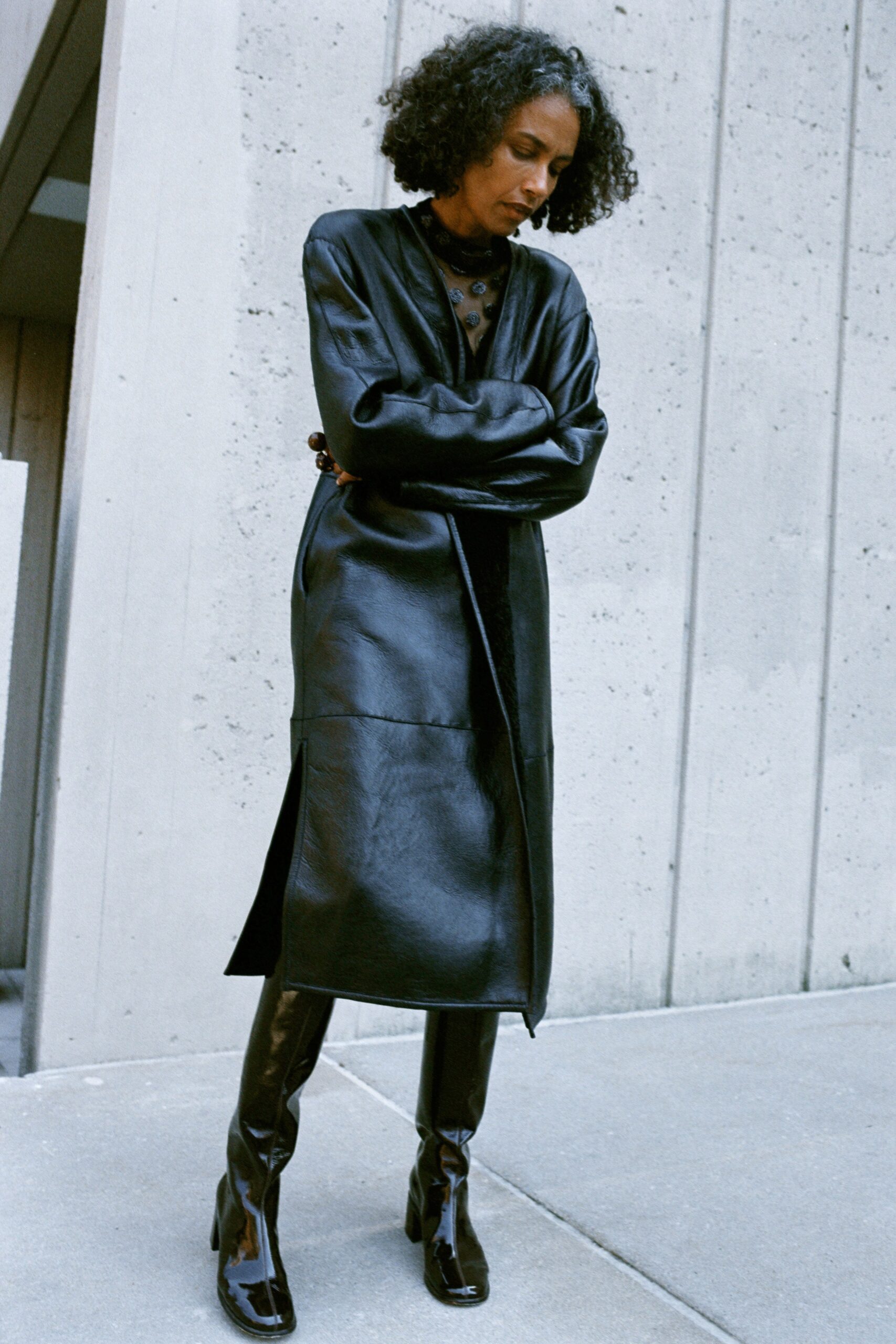A fitted black leather coat with long sleeves and asymmetric design paired with black leather pants.