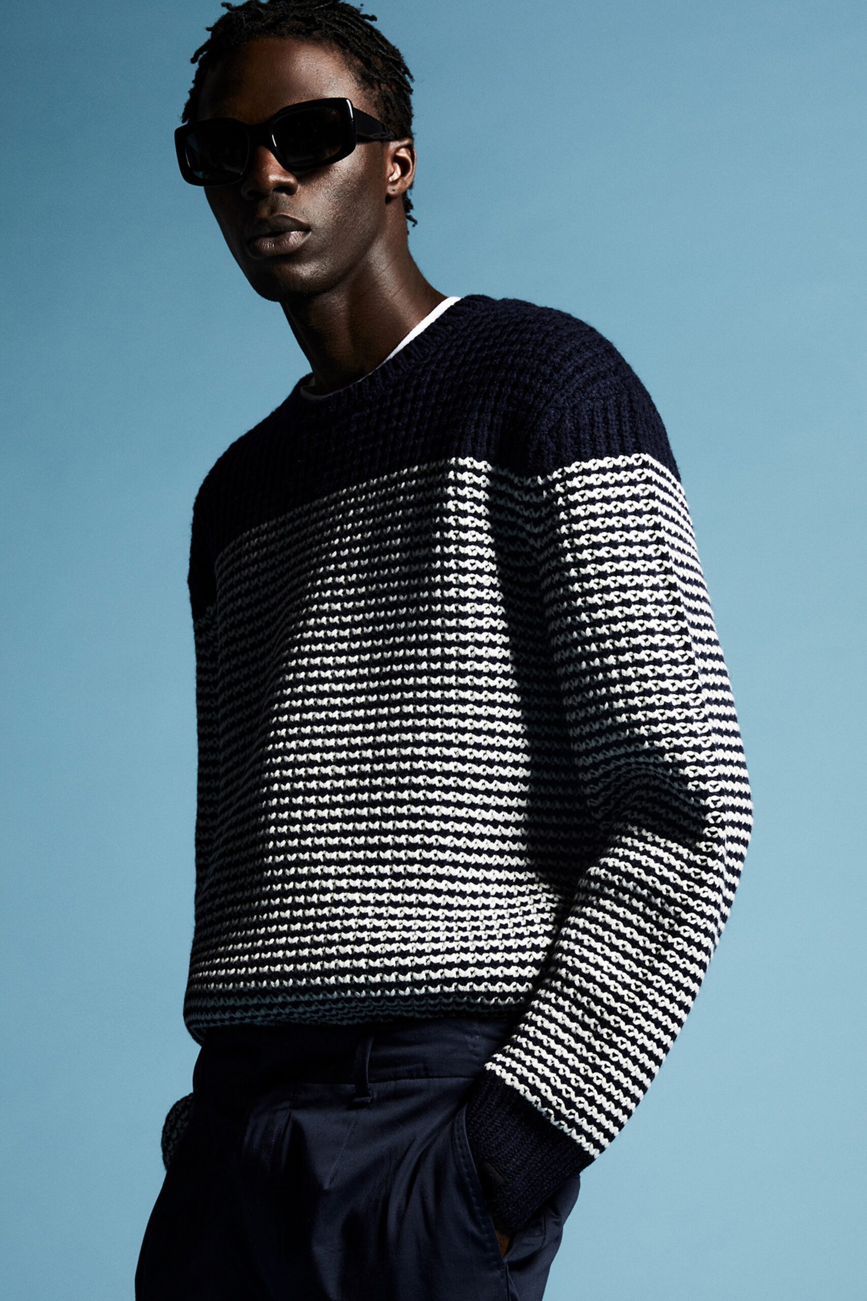 A fitted black and white striped sweater with long sleeves and a crew neckline.