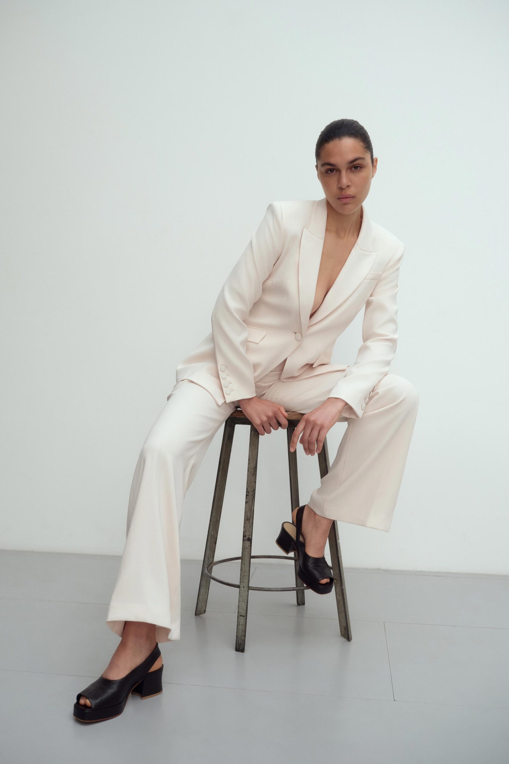 A tailored beige suit with long sleeves and a collared design, featuring straight-leg trousers.