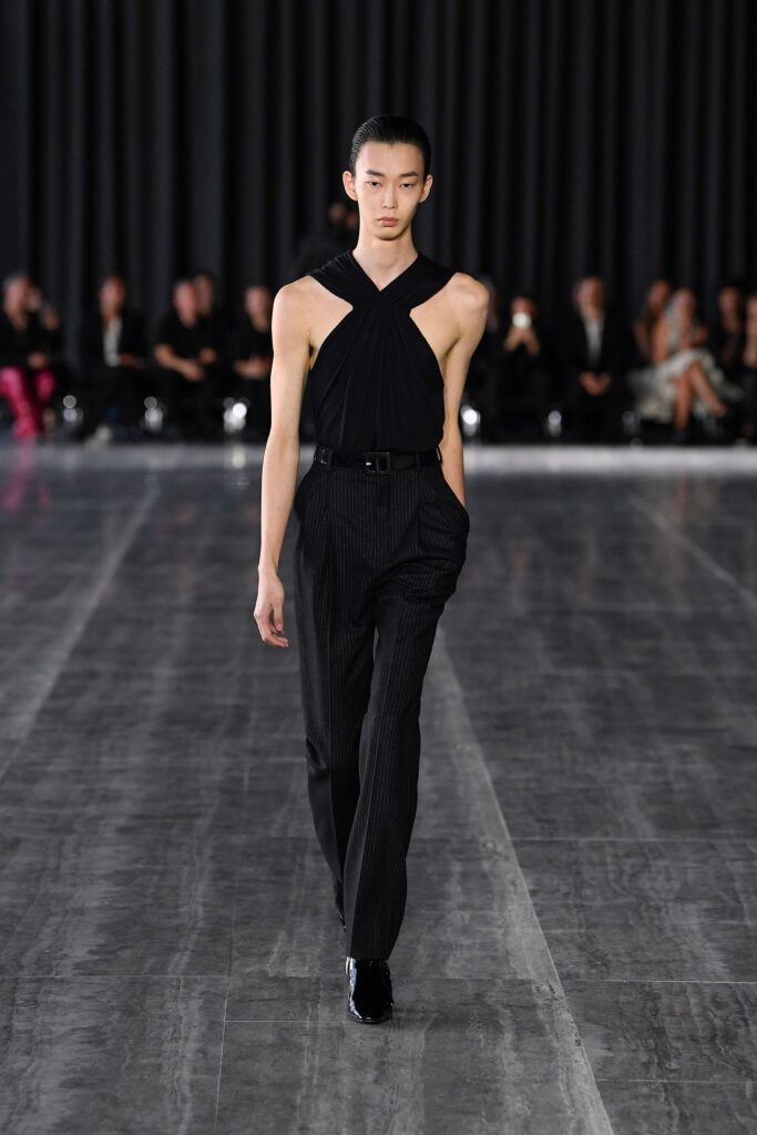 A fitted black sleeveless top with a V-neck and striped pants, creating a sleek silhouette.