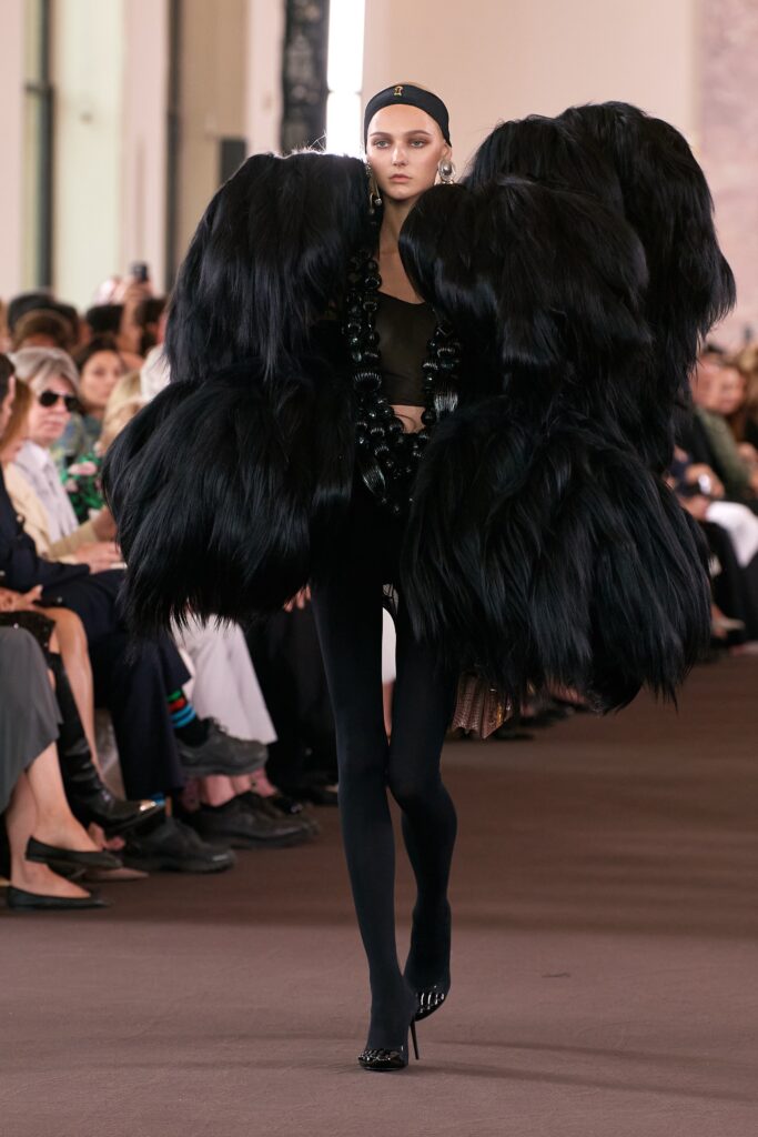 An oversized black fur coat with long sleeves and a layered design.