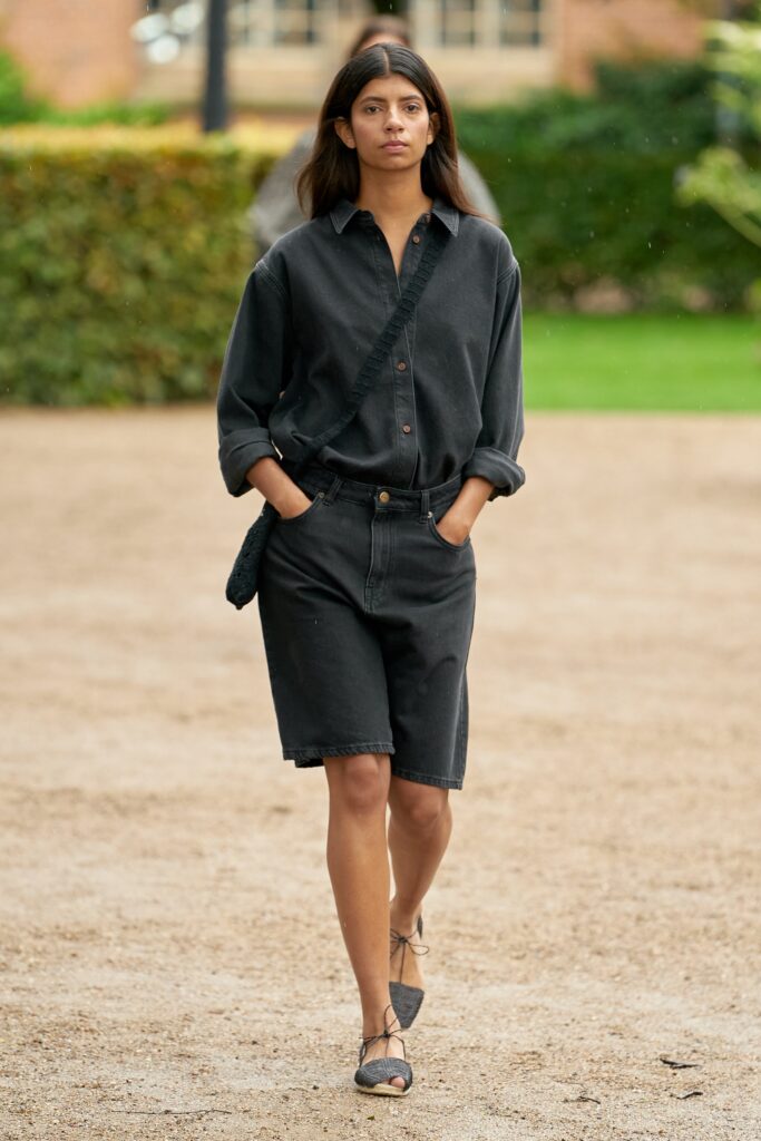 A relaxed black denim shirt with long sleeves and a collared design, paired with matching shorts.
