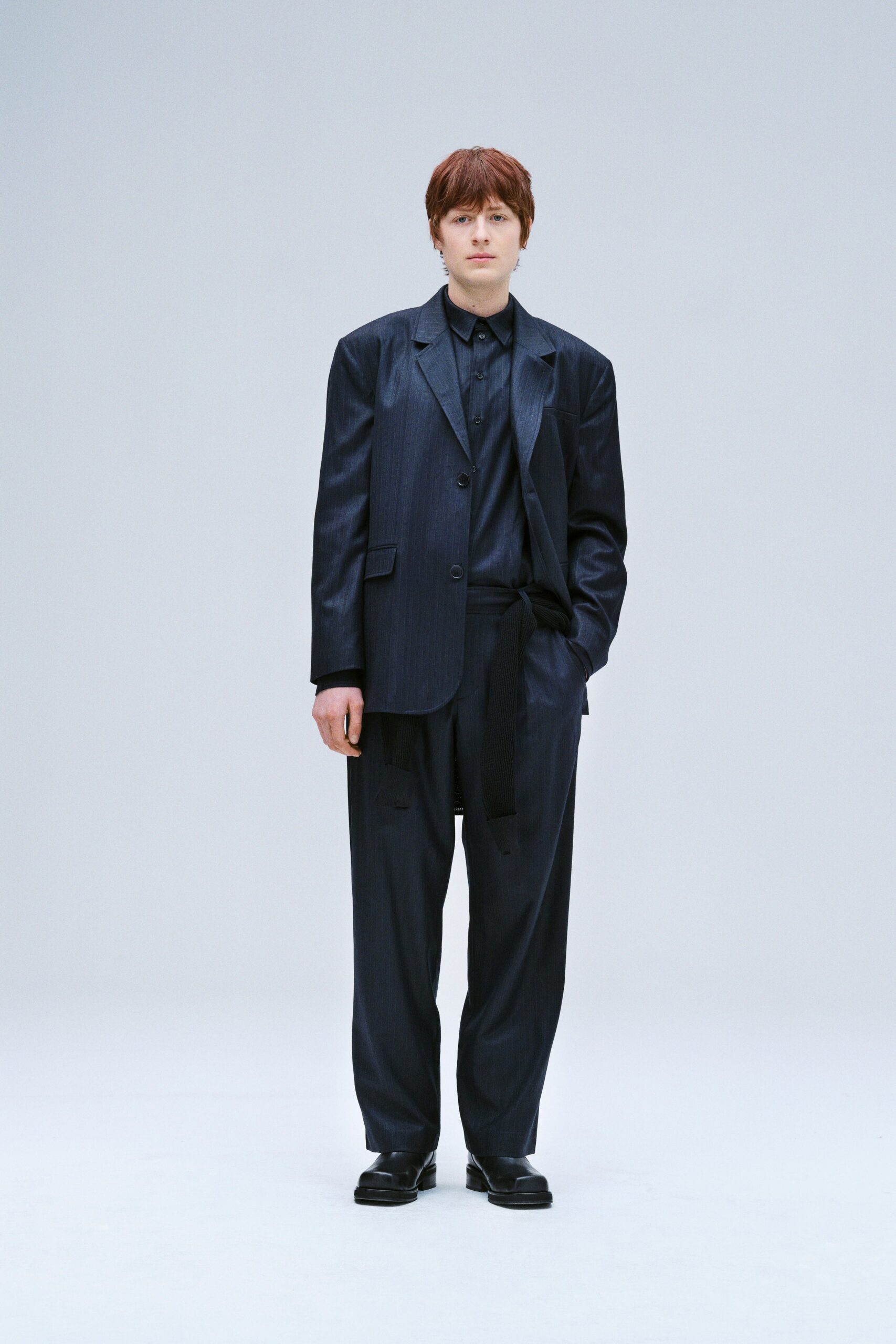 A relaxed black wool suit featuring a long-sleeve collared shirt and straight-leg trousers.