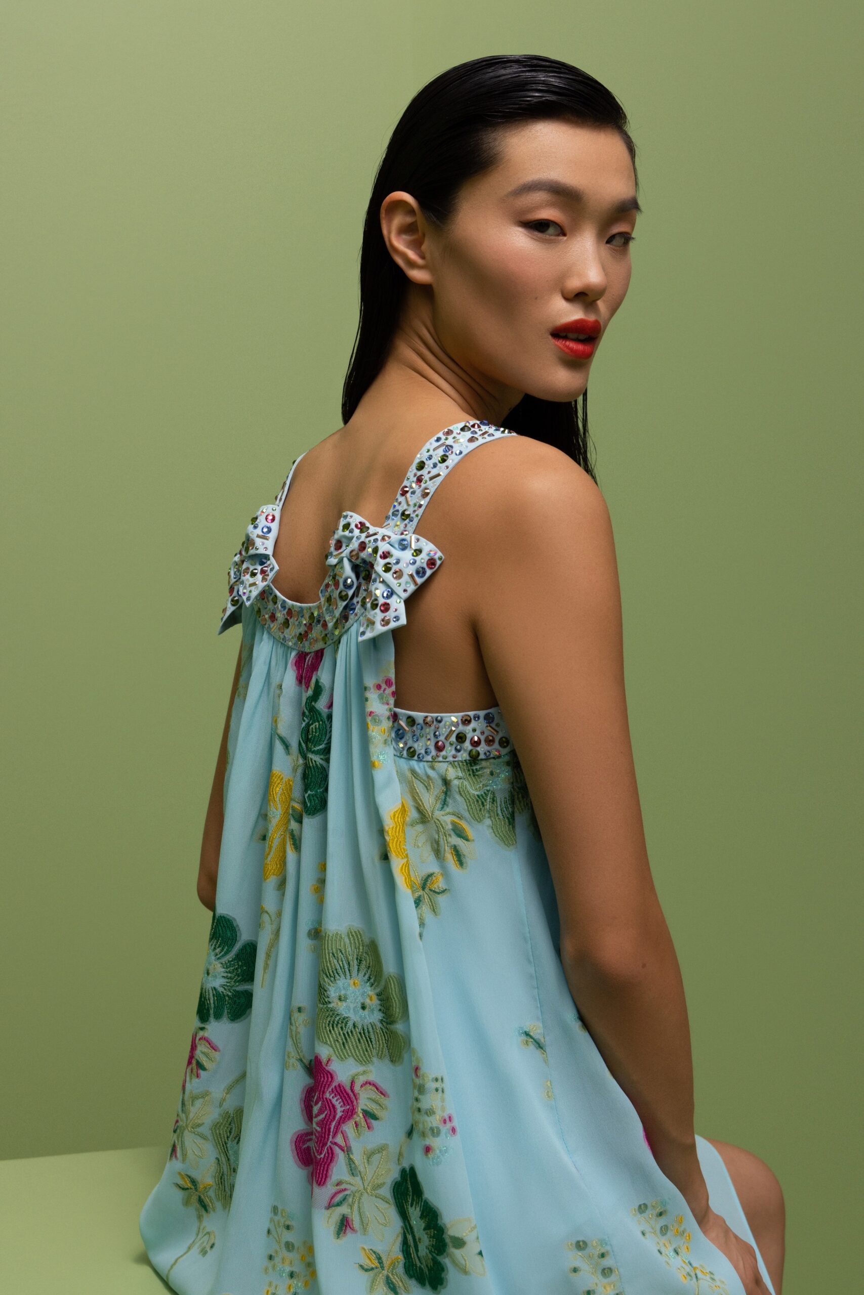 A relaxed blue silk sleeveless dress with a backless design and floral tiered details.