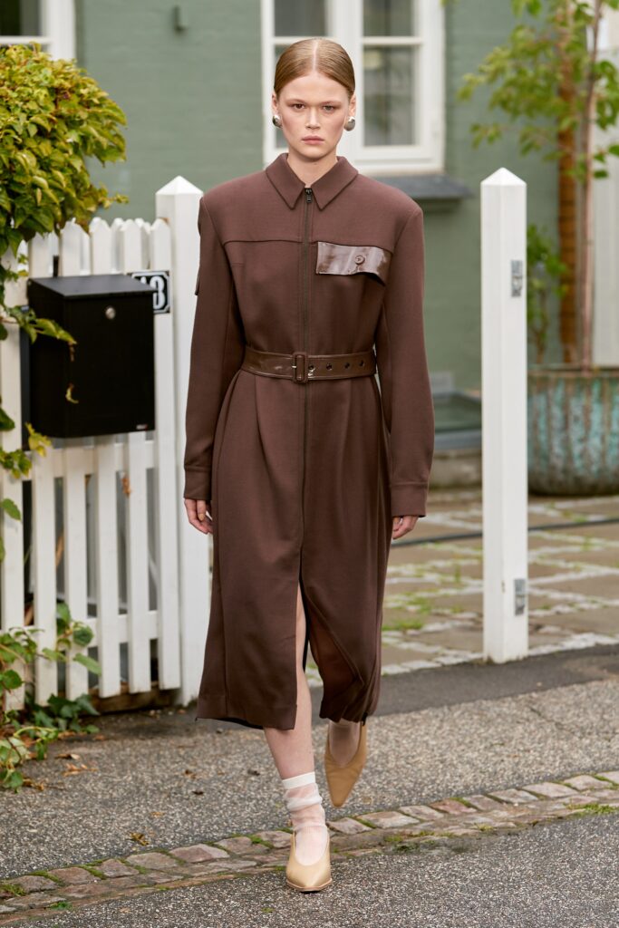 A fitted brown cotton dress with long sleeves, a collared neckline, and a belted waist featuring a slit.