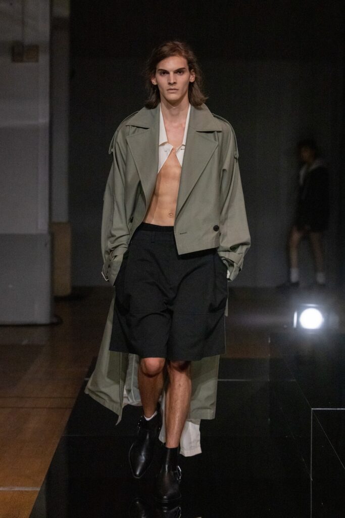 A relaxed green coat paired with black shorts, featuring a collared design and buttoned details.