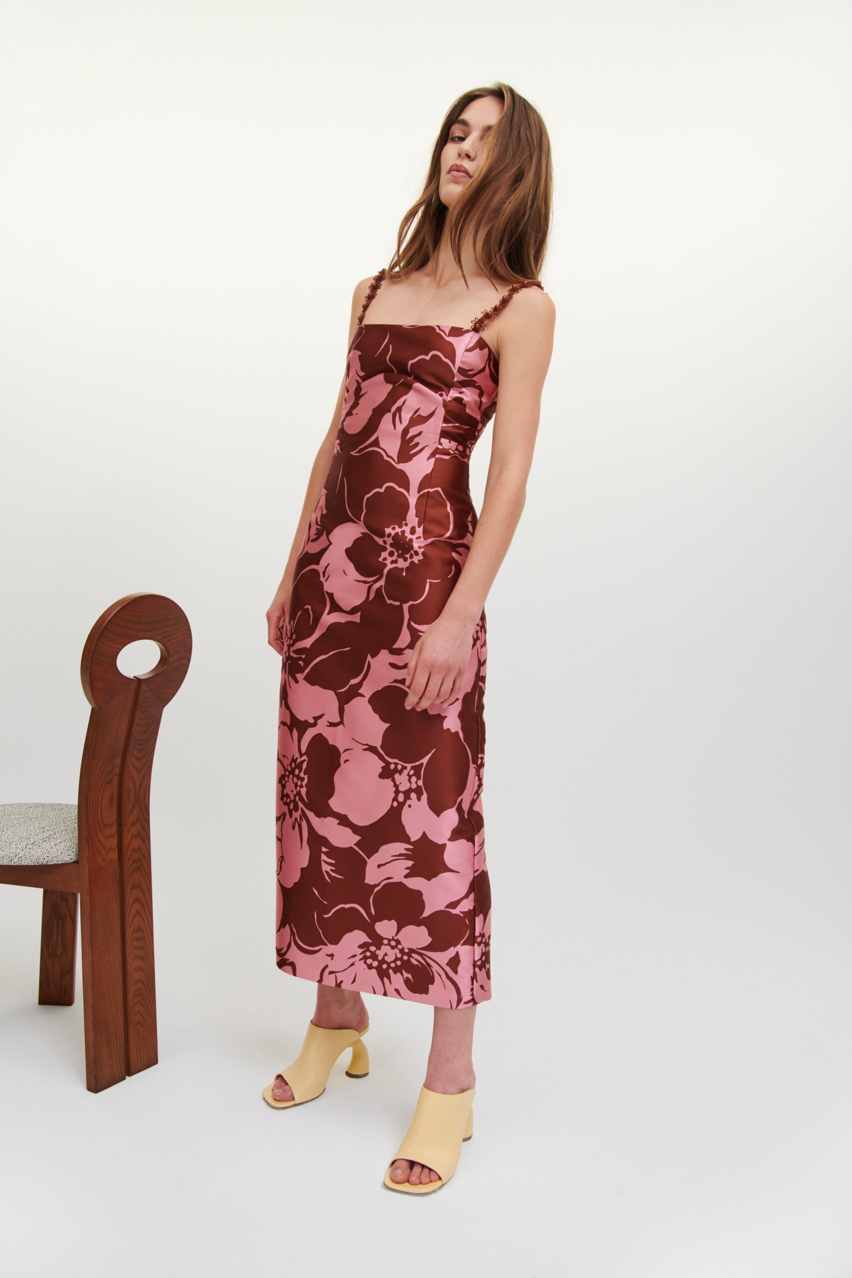 A fitted pink and brown floral dress with a sleeveless design and V-neckline.