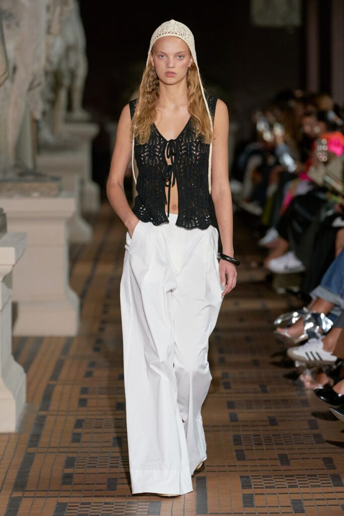 A relaxed black cotton sleeveless top paired with wide-leg white pants, creating a chic ensemble.