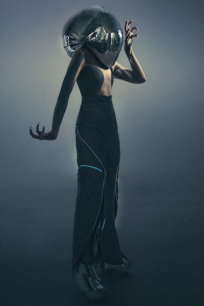 A fitted black silk sleeveless dress with an asymmetric design detail.