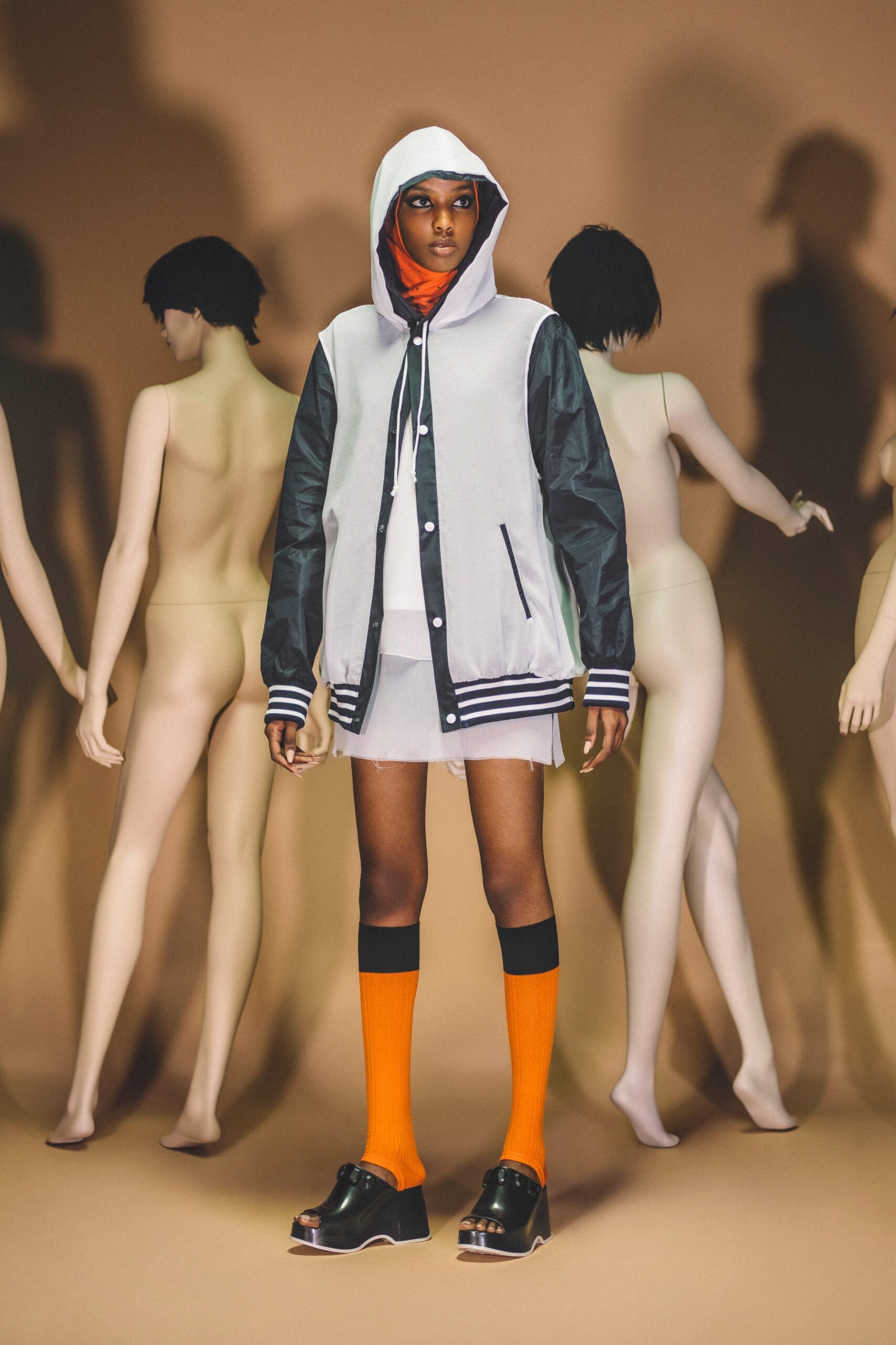 A relaxed gray hooded jacket layered over a dress, complemented by vibrant orange socks.