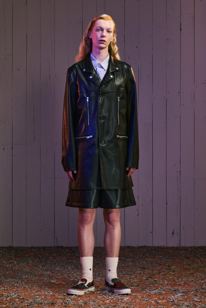 A fitted black leather dress with a collared neckline and asymmetric design.