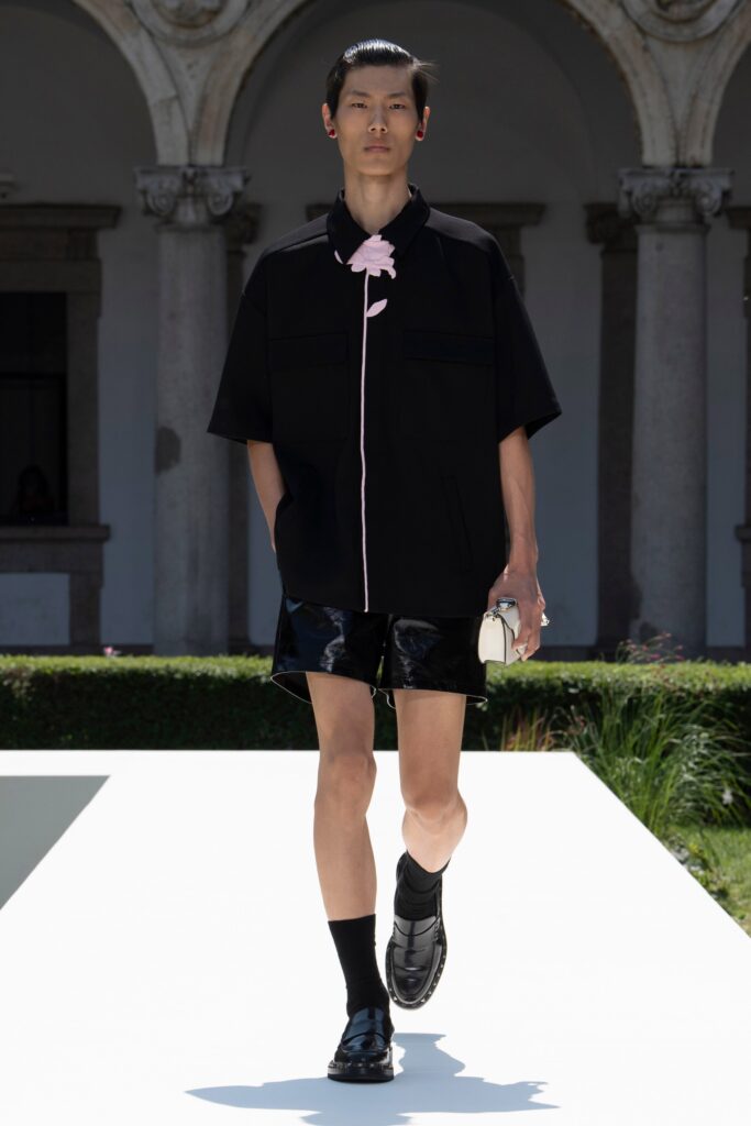 A relaxed black shirt with a collar and short sleeves, paired with shiny black shorts.