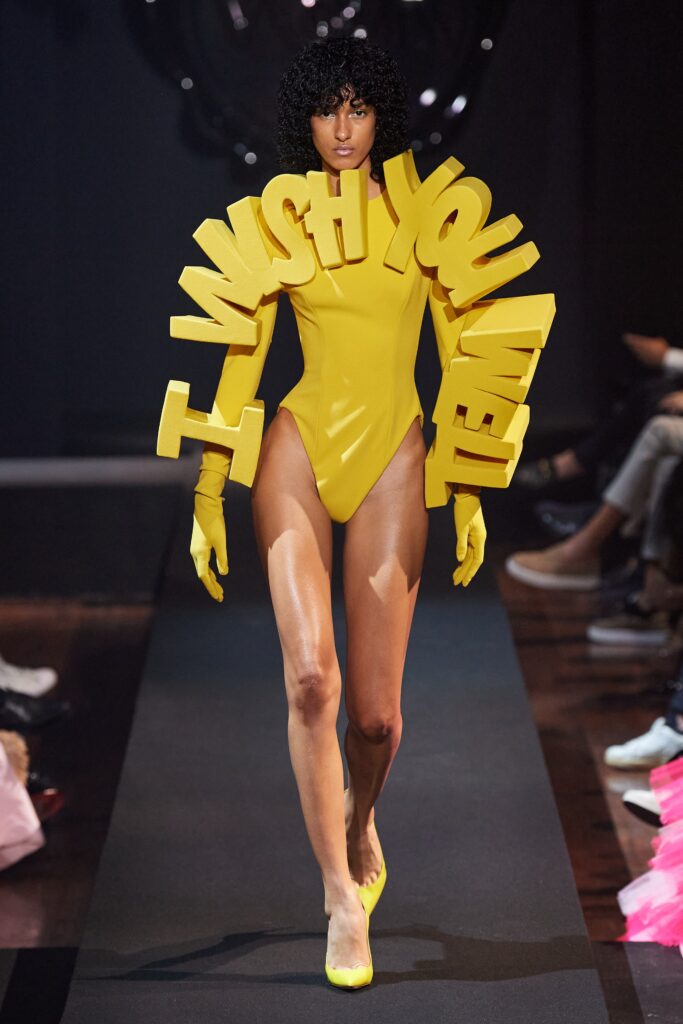 A fitted yellow bodysuit with long sleeves and a high neckline featuring a printed design.