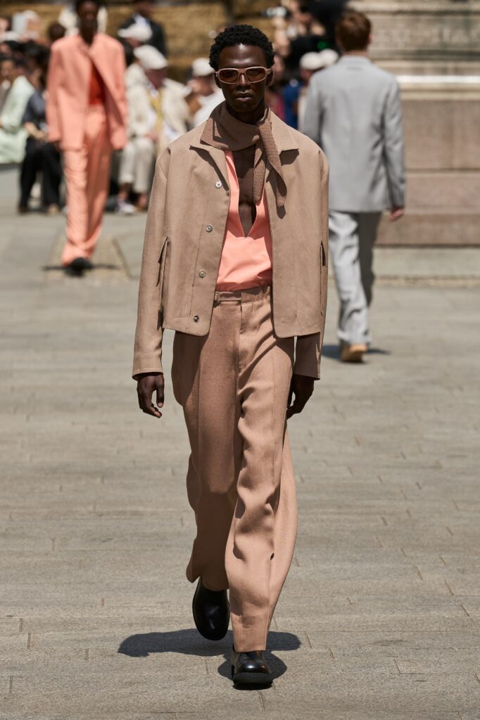 A relaxed beige cotton jacket with long sleeves and a collared design, paired with wide-leg pants.