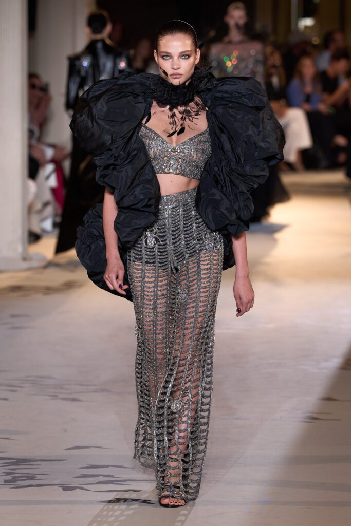 A fitted silver sequined sleeveless top with high-neck and matching pants, featuring an asymmetric design.