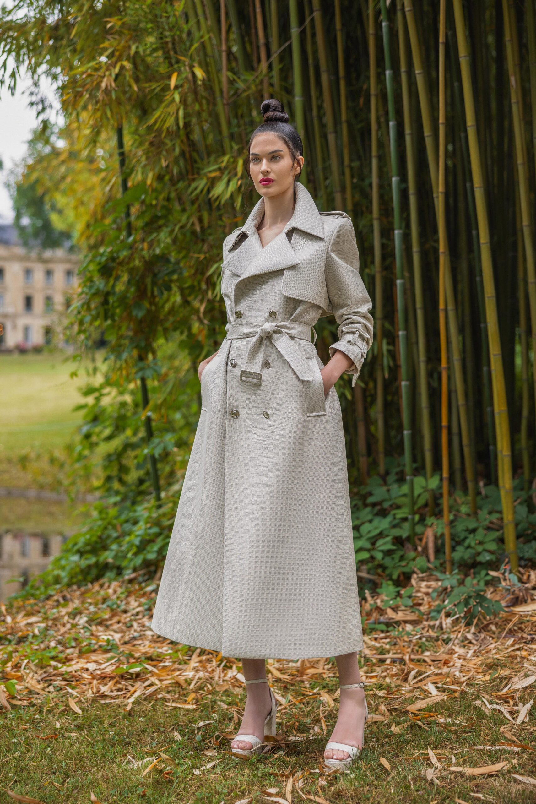 A fitted beige wool coat with long sleeves, a collared neckline, and a belted design.