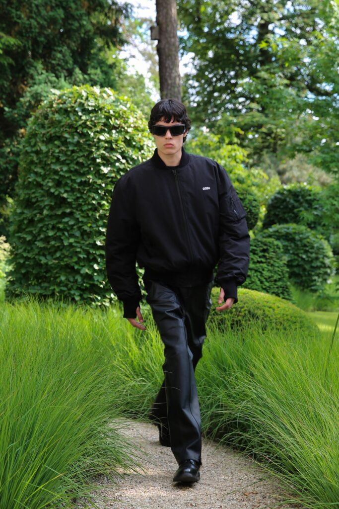 A relaxed black jacket with long sleeves paired with matching black pants featuring zippered details.