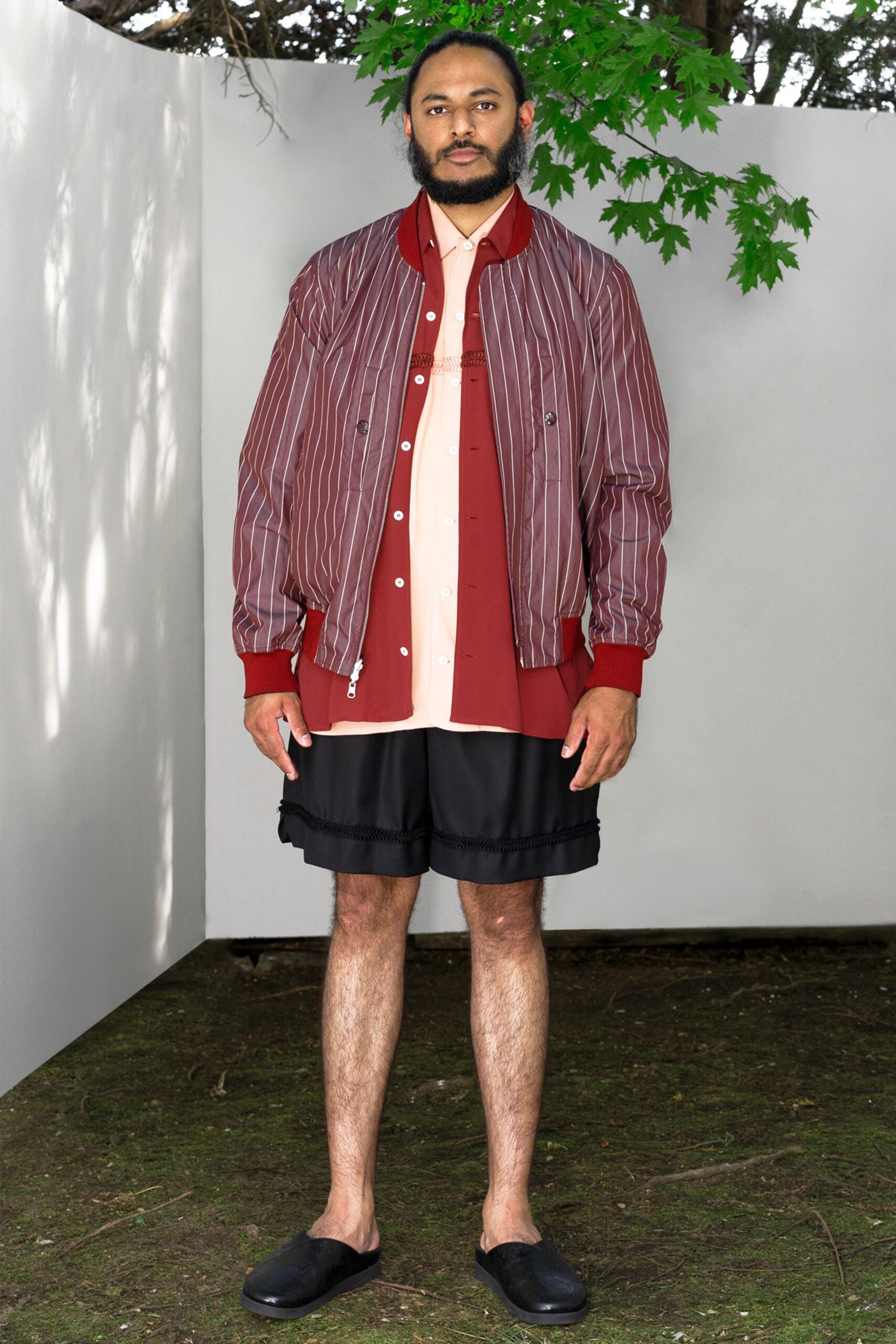 A relaxed fit red striped jacket paired with black shorts and a collared shirt.