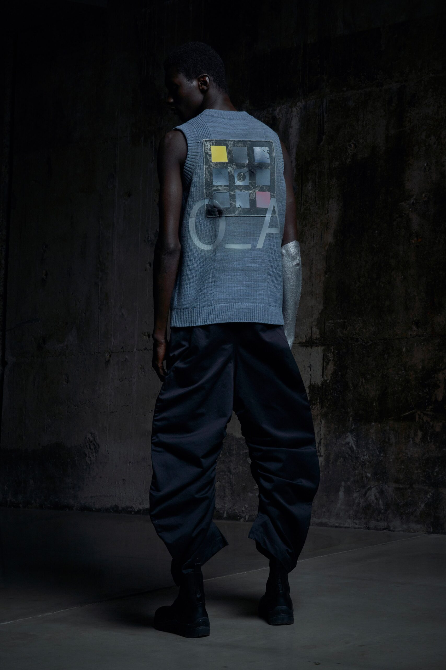 A relaxed gray sleeveless vest paired with black pants featuring an asymmetric design.